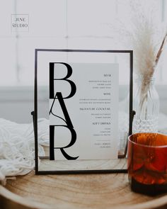 a table with a glass and some type of paper on it next to a candle