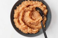 a bowl filled with mashed potatoes on top of a white table next to a spoon