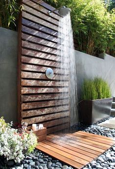 an outdoor shower with water flowing from the faucet and wooden planks on the ground