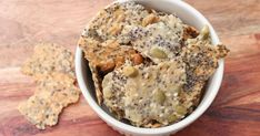 a white bowl filled with cookies and nuts on top of a wooden table next to a small cracker