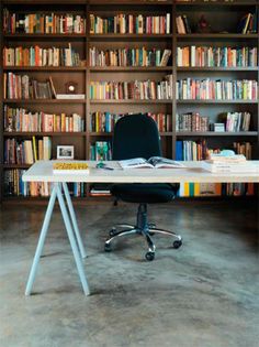 an office desk with bookshelves in the background and a chair at one end