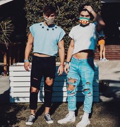 two young men standing next to each other in front of a house wearing face masks