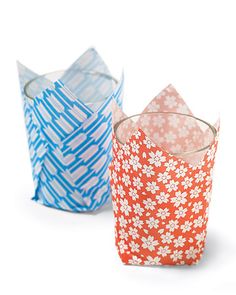 three different colored paper cups sitting next to each other on a white surface, one with an origami design