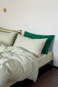 a bed with green and white pillows on it