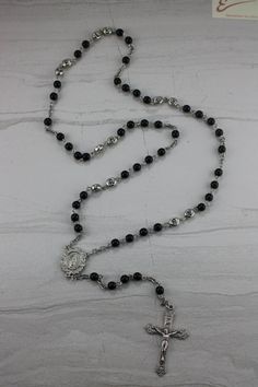 This is a beautiful personalized keepsake rosary. The beads are black onyx and the initials are pewter. This is a touching gift perfect for the special man in your life. This is great for a father or grandfather with many grandchildren. We can also make this with full first names or first, middle, and last name perfect for a boy's First Communion Gift. Whatever your needs, we can do it for you! Personalized Black Spiritual Jewelry, Personalized Black Spiritual Necklaces, Personalized Spiritual Black Necklaces, Adjustable Silver Rosary With Black Beads, Black Cross Rosary As Gift, Silver Rosary With Black Beads And Crucifix, Silver Rosary With Black Beads As Gift, Gift Black Rosary With 8mm Beads, Black Crucifix Rosary Bracelet As Gift