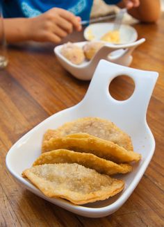 some food is sitting on a white dish and in front of a child at a table