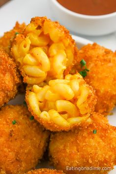 fried macaroni and cheese balls on a plate with dipping sauce in the background