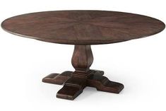 a round wooden table with four pedestals on one end and two leaves on the other