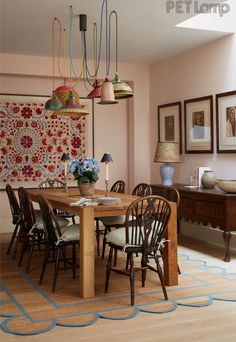 a dining room table with chairs and pictures on the wall in the back ground area