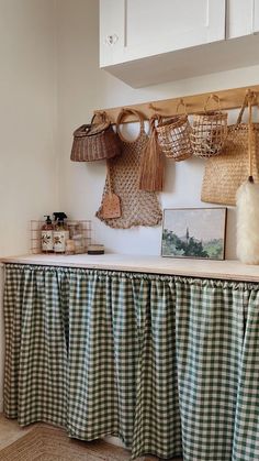 some baskets hanging on the wall above a table with green and white checkered cloth