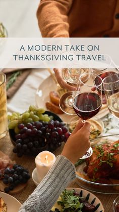 people toasting wine glasses at a thanksgiving dinner table with turkey, grapes and other foods