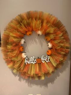 an orange and yellow tulle wreath with the word hello fall written in white on it