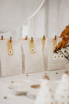 three bags with small flowers in them sitting on a table next to a vase filled with dried flowers