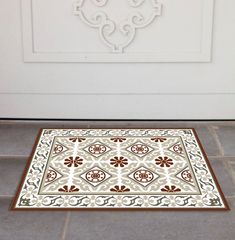 a door mat on the floor in front of a white door with a decorative design