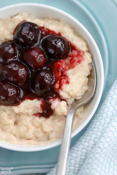 a bowl filled with oatmeal and cherries next to a blue towel