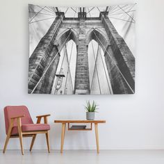 a chair and table in front of a wall hanging on the wall with a black and white photo