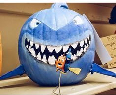 a pumpkin shaped like a shark with teeth on it's face and other decorations around the mouth