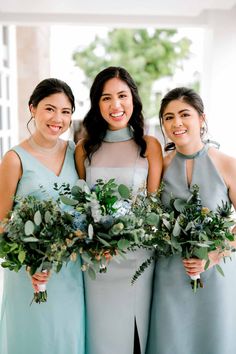 three bridesmaids holding their bouquets and smiling at the camera