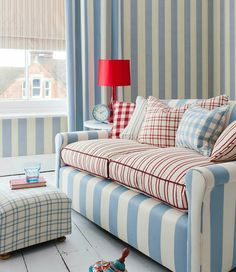 a blue and white striped couch sitting in front of a window next to a foot stool