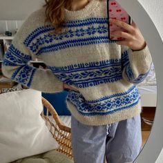 a woman taking a selfie in front of a mirror wearing a sweater and pyjama pants