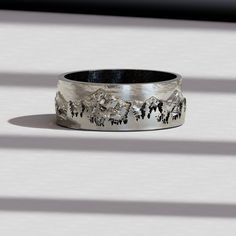 a silver ring with horses on it sitting on top of a white table next to a window