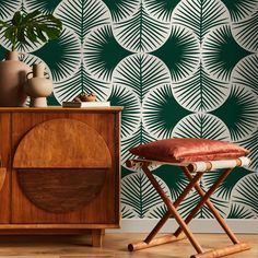 a green and white wallpaper with palm leaves on it, next to a wooden chair