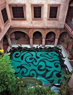 an aerial view of a pool in the middle of a building with lots of plants around it