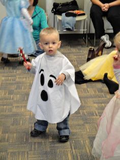 two children dressed up as ghost and princesses in an office setting with people sitting on the floor