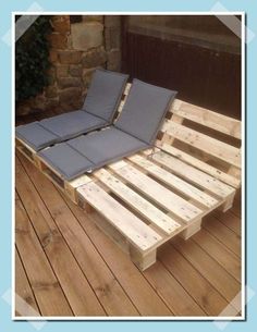 a bed made out of wooden pallets on top of a deck with blue cushions