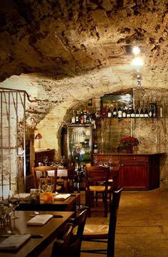 an empty restaurant with tables and chairs in the center, along with wine bottles on the wall