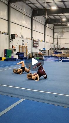 two women are performing an acrobatic exercise on the floor in a gym