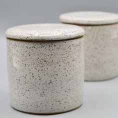 two white ceramic jars with speckles on them