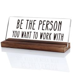 a desk sign that says be the person you want to work with on top of a wooden block