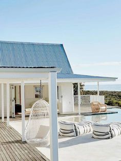 a white house with a pool and chairs on the deck