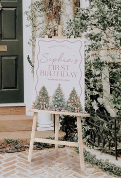 a welcome sign for someone's first birthday in front of a house with greenery