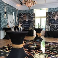 a room filled with tables and chairs covered in black cloths, surrounded by wallpaper