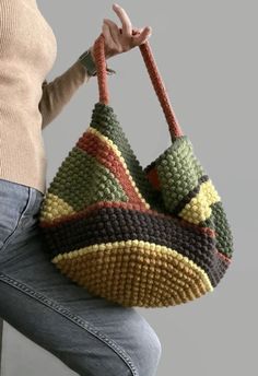 a woman is holding a crocheted purse