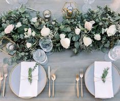 the table is set with white flowers and greenery