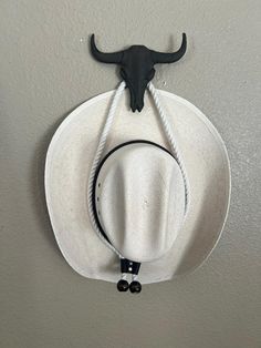 a cowboy hat hanging on the wall with two earbuds attached to it's side