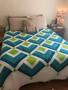 a bed with a blue and green quilt on it