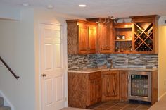 a kitchen with wooden cabinets and tile flooring next to a wine rack on the wall