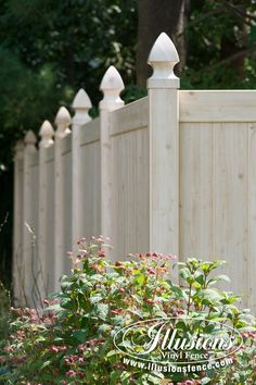 a white picket fence surrounded by flowers and trees