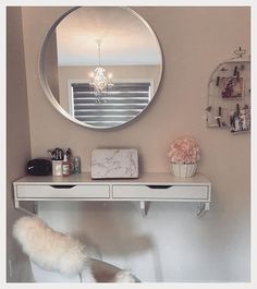 a white desk topped with a mirror next to a wall mounted shelf filled with makeup