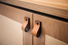 a close up of two handles on a cabinet with wood grained finish and leather straps