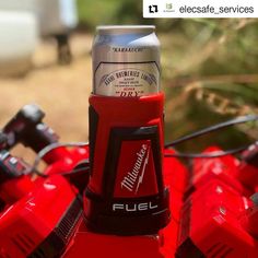 a can of beer sitting on top of a red bike