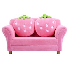 a pink couch with two stuffed strawberries on it's back and green leaves