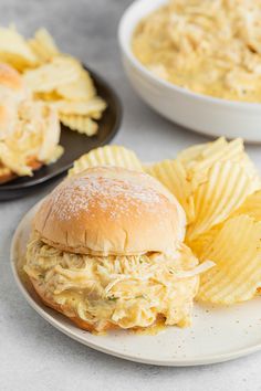 a plate with a sandwich and chips on it next to a bowl of cole slaw