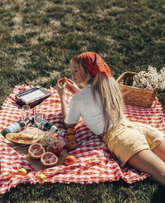 a woman sitting on a blanket eating food