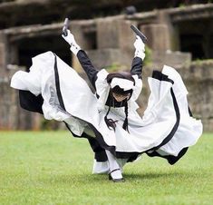 a woman dressed in black and white dancing on grass