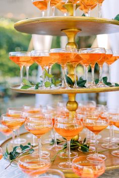 there are many glasses that are on the trays with drinks in them and one is filled with orange liquid